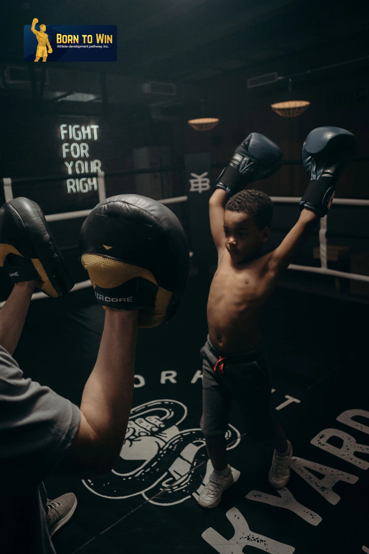 Young boxer with both arms raised after a pad round